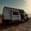 Furgoneta camper blanca estacionada al atardecer frente al mar
